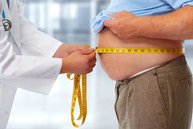 Médico medindo a barriga de um homem com uma fita