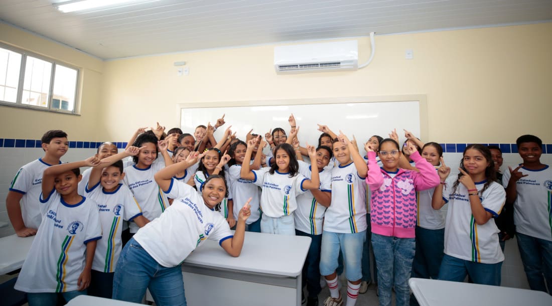 Alunos na sala de aula apontando para o ar condicionado
